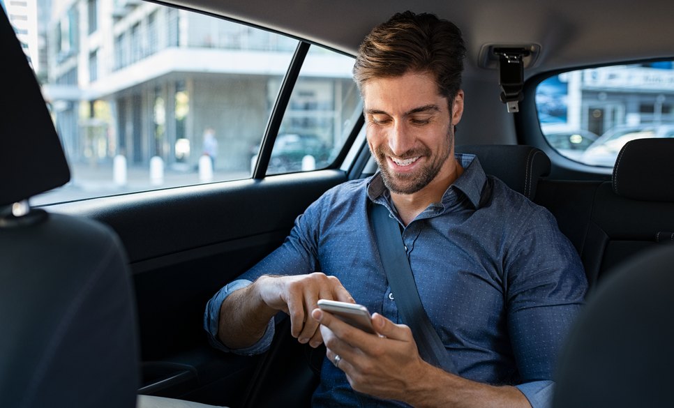 Investor reading company news on a phone in the back of a car