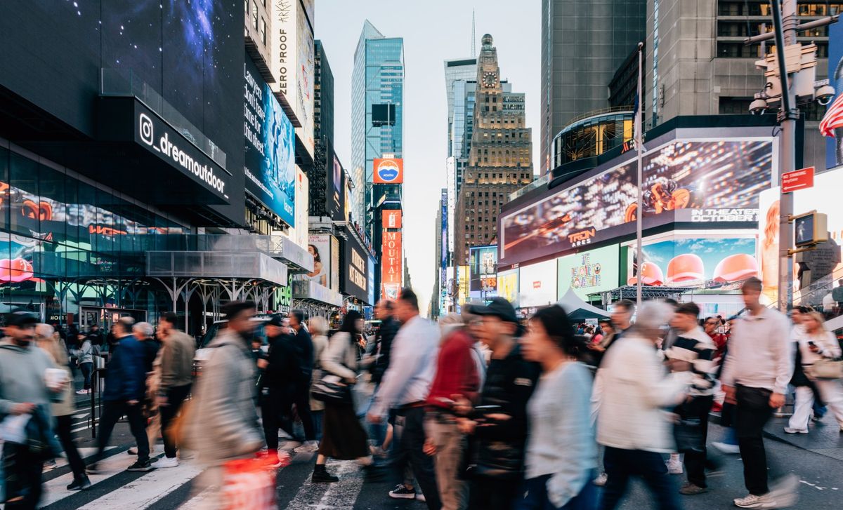 Pedestrians crossing Times Square beneath digital billboards